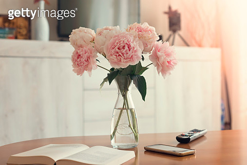 Vase of peonies,smartphone,book,and remote control on the Wooden living room table - gettyimageskorea