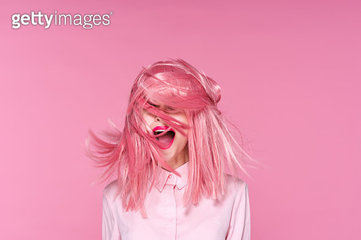 Woman on pink background with flying pink hair, portrait - gettyimageskorea