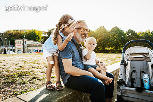 Two kids having fun and playing with their grandpa while out at the park together. - gettyimageskorea
